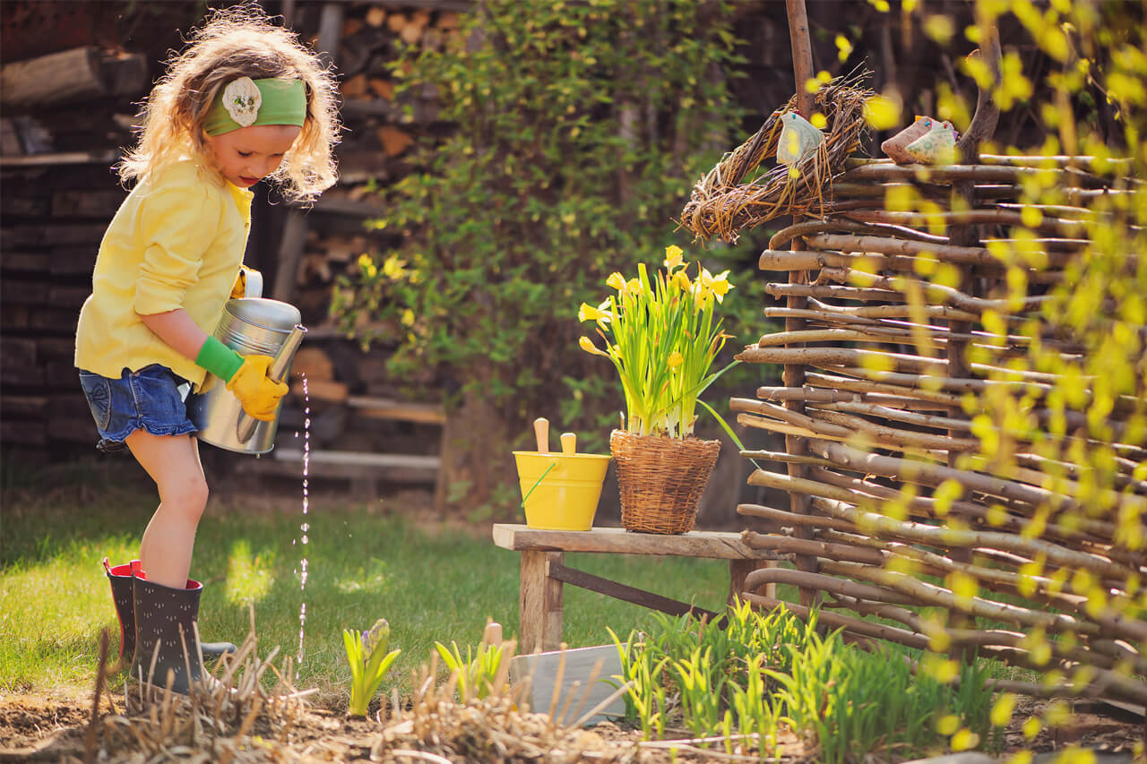 Campagnebeeld Onweerstaanbaar Someren met een kind dat de planten in de tuin water geeft